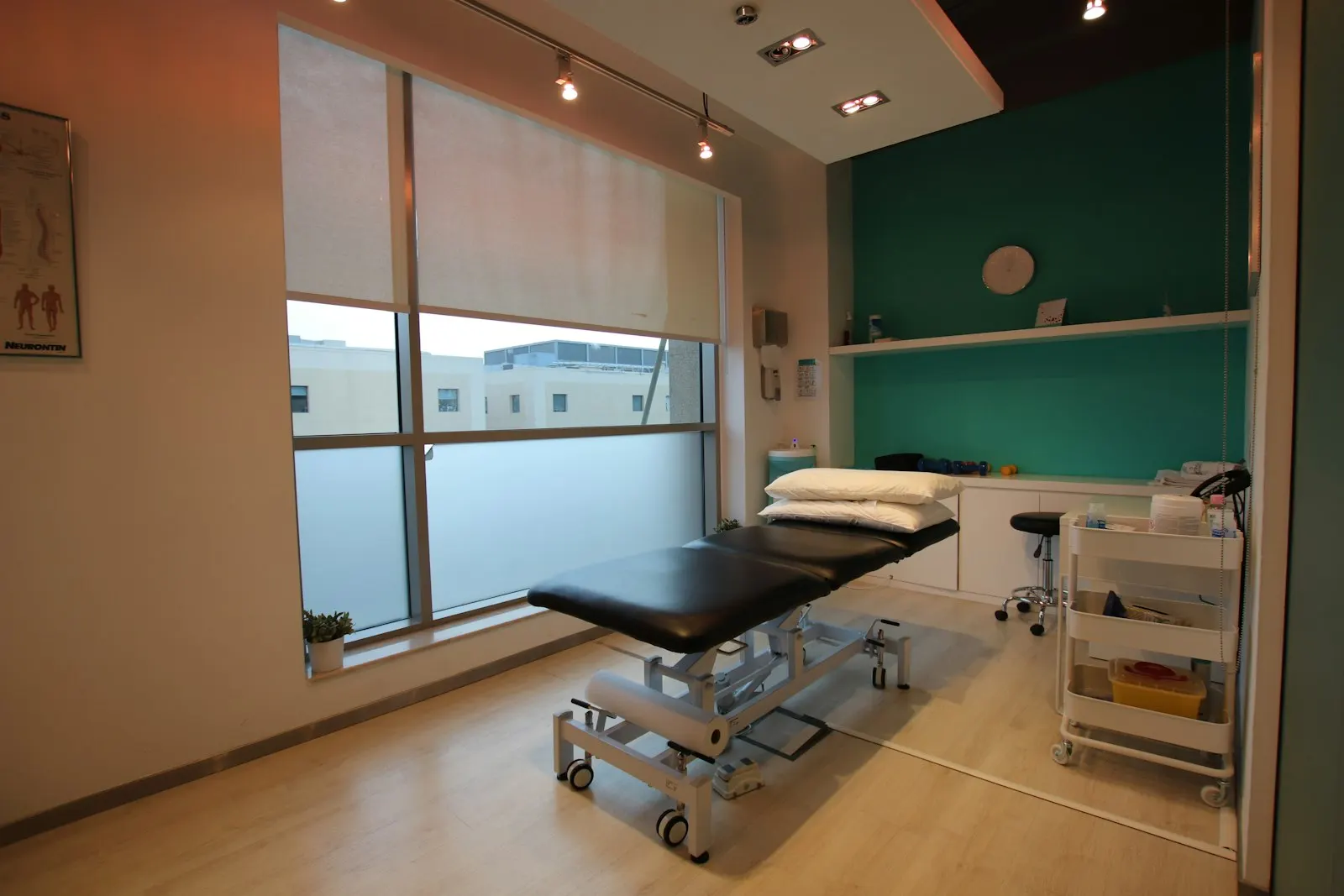 A chiropractic treatment room with a spinal anatomy chart on the wall